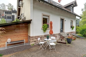 Une maison dotée d’un patio, d’un espace salon extérieur et de plantes en pot.