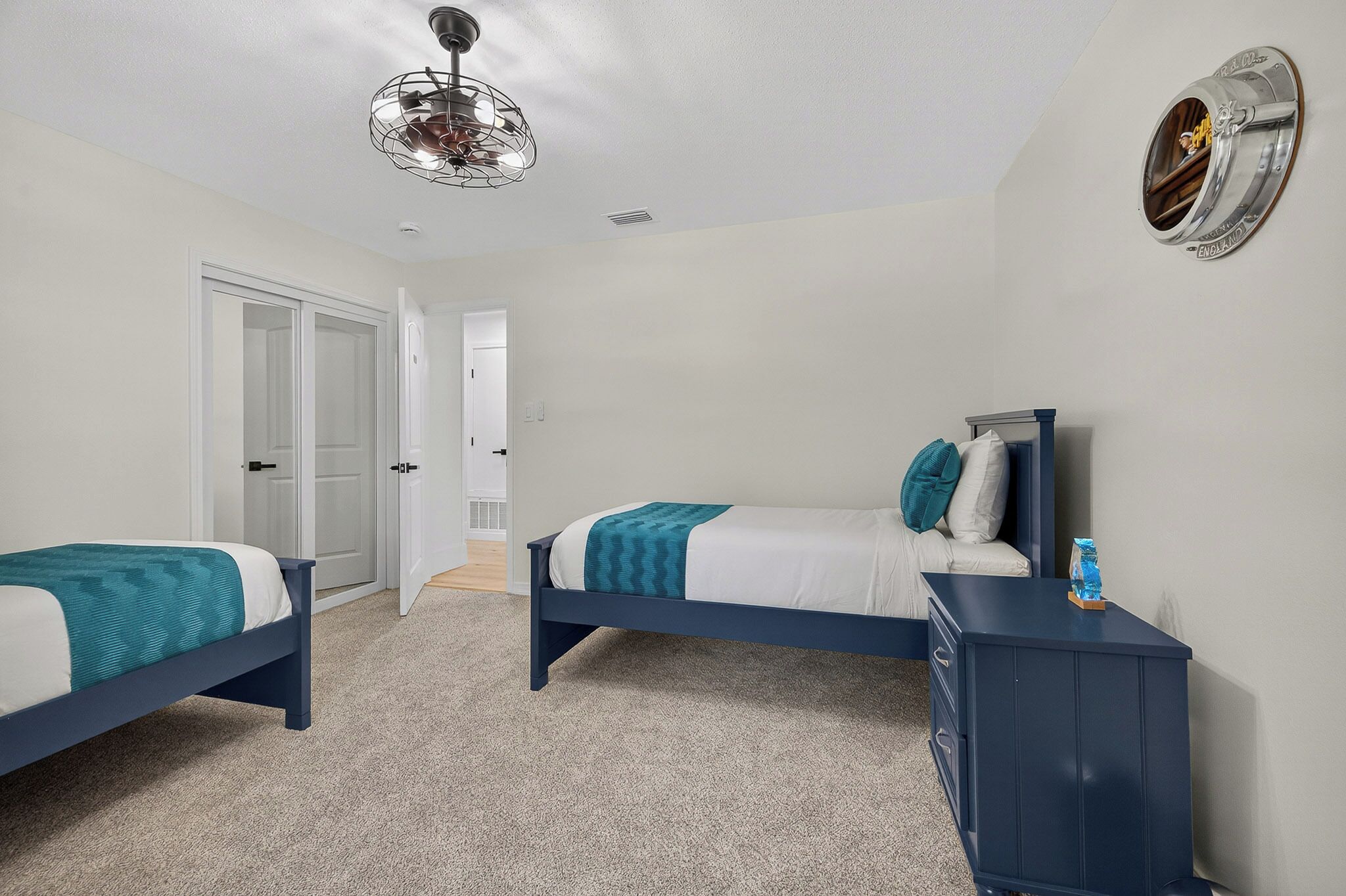 A bedroom with two beds, a dresser, and a ceiling fan.