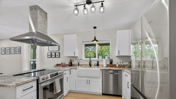A modern kitchen with white cabinets, stainless steel appliances, and a large window providing natural light. - The Skipper’s Hideaway: Golf Course & Pool Oasis (Daphne)