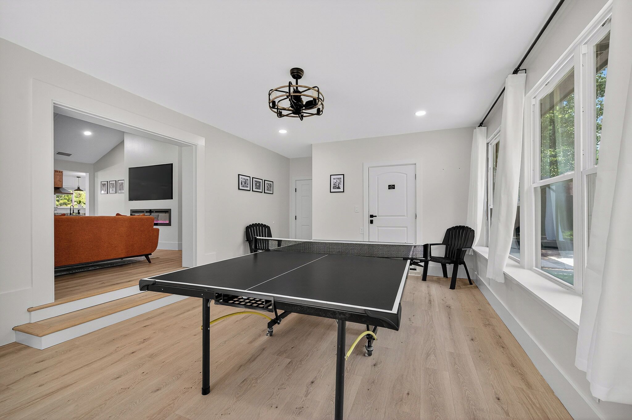 A ping pong table in a room with wooden flooring, white walls, and a ceiling light fixture.