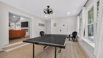 A ping pong table in a room with wooden flooring, white walls, and a ceiling light fixture.