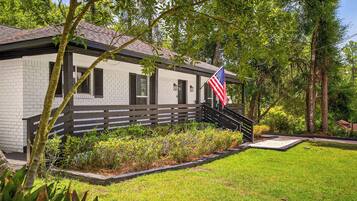 A white brick building with a black roof, a wooden fence, and an American flag.