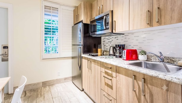 A modern kitchen with wooden cabinets, a stainless steel sink, a microwave, and a red toaster.