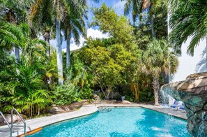 A swimming pool surrounded by lush greenery and a waterfall feature.