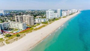 A coastal cityscape with high-rise buildings along the beachfront, a sandy beach, and a clear blue ocean.