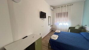 A hotel room with a bed, a TV mounted on the wall, a desk with a chair, and a window with curtains. - B&B CASA LAMANNA- Room No. 5 (Torretta)
