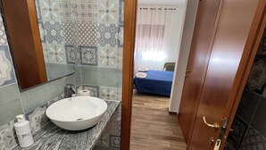 A bathroom with a marble sink, a mirror, and a shower area. - B&B CASA LAMANNA- Room No. 5 (Torretta)