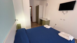 A bedroom with a bed, a TV mounted on the wall, and a small desk with a chair. - B&B CASA LAMANNA- Room No. 5 (Torretta)