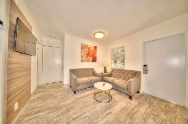 A modern living room with two sofas, a coffee table, a painting, and a TV on the wall. - Riverside Vacation Rentals by Rocketstay (Pompano Beach)