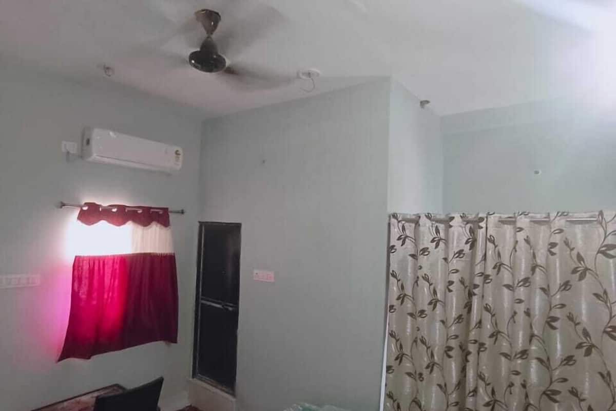 A bedroom with a bed, a desk, a chair, a window, and a curtain.