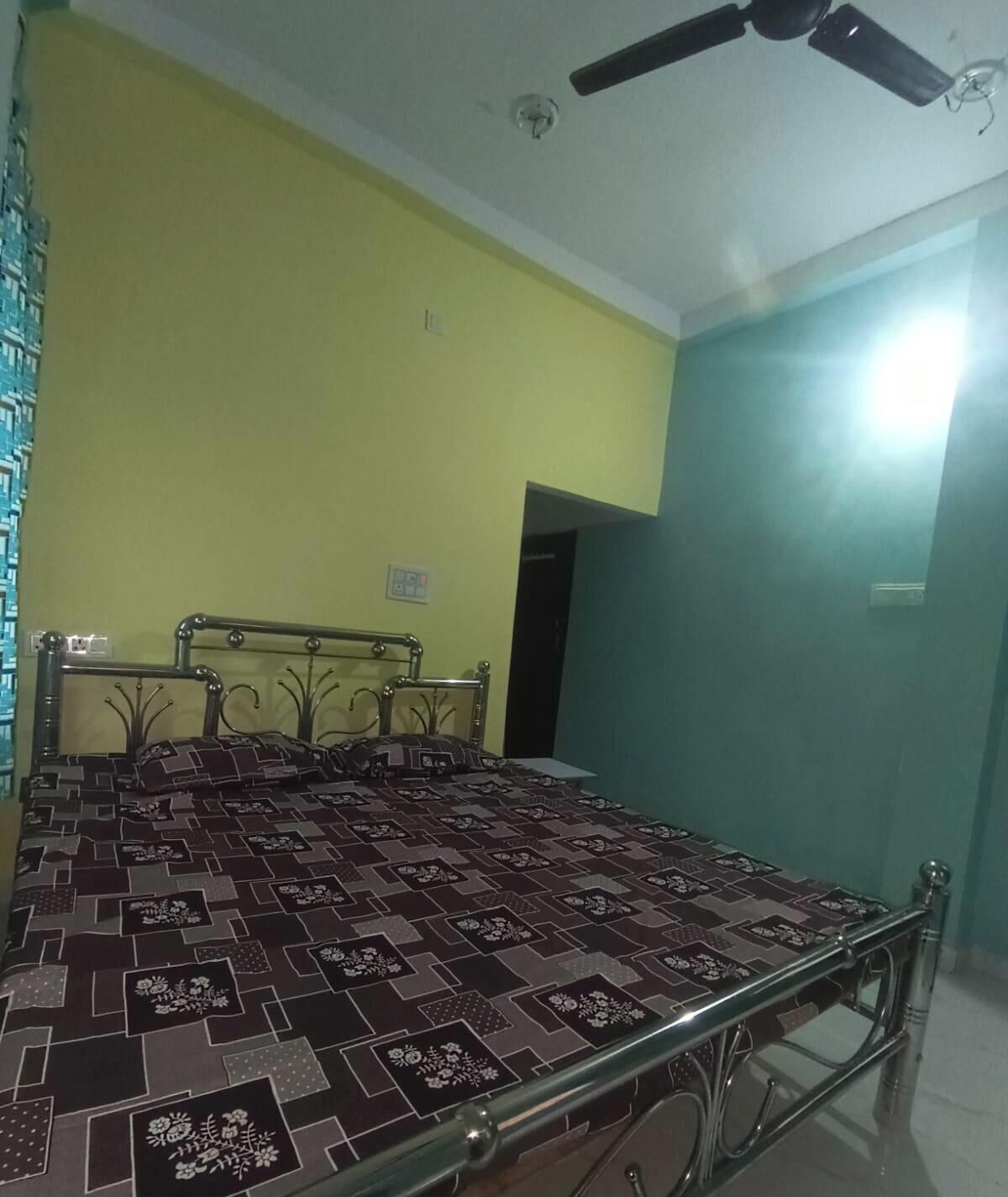 A room with a bed, a ceiling fan, and a door.