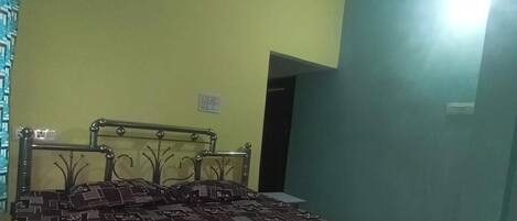 A room with a bed, a ceiling fan, and a door.