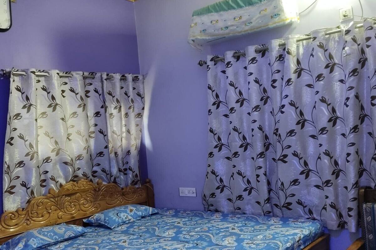 A bedroom with a wooden bed, purple walls, and floral curtains.