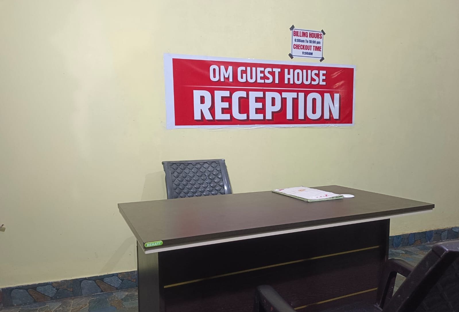 Ein Empfangsschalter mit einem Schild darüber, auf dem 'OM GUEST HOUSE RECEPTION' steht.