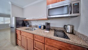 A modern kitchen with granite countertops, stainless steel appliances, and wooden cabinets. - Beach Walk Studio w/Pool & 2 Queens (Pompano Beach)