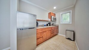 A compact kitchen with a refrigerator, microwave, and wooden cabinets. - Pool View Studio W/2 Queens (Pompano Beach)