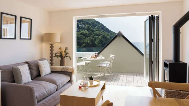 Ein gemütliches Wohnzimmer mit einer Couch, einem Tisch mit Getränken und einem Balkon mit Tisch und Stühlen.