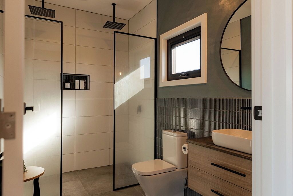 Une salle de bain moderne dotée d’une douche à parois de verre, de toilettes et d’un meuble-lavabo avec un évier.