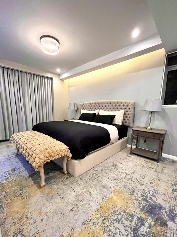 Un dormitorio moderno con una cama grande, una mesita de noche, una lámpara y vistas al exterior.