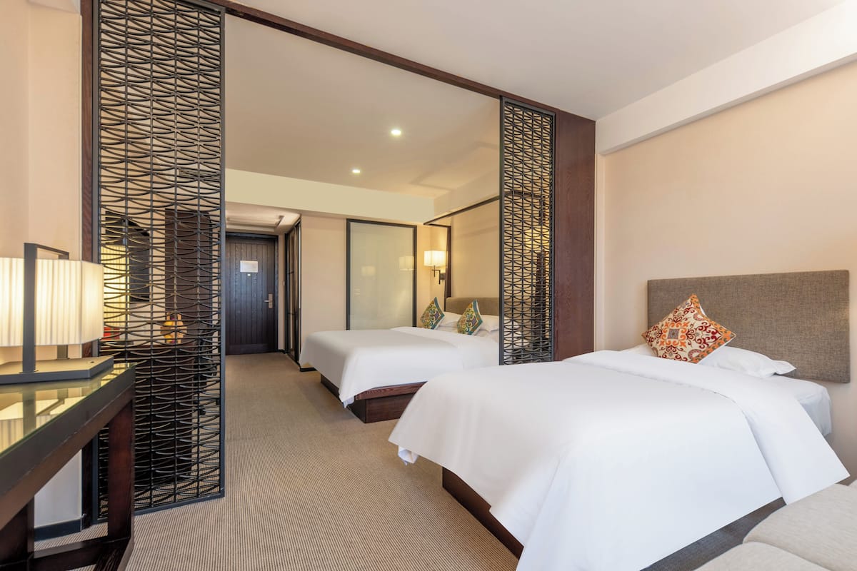 Ein Hotelzimmer mit zwei Betten, einem Schreibtisch und einem Spiegel.