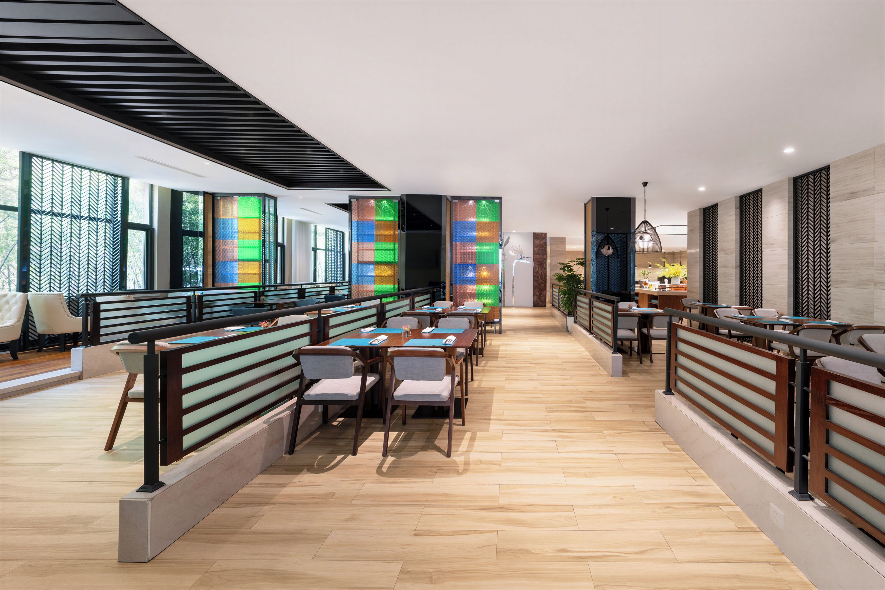 A modern interior with a long dining area, wooden flooring, and a mix of seating arrangements.