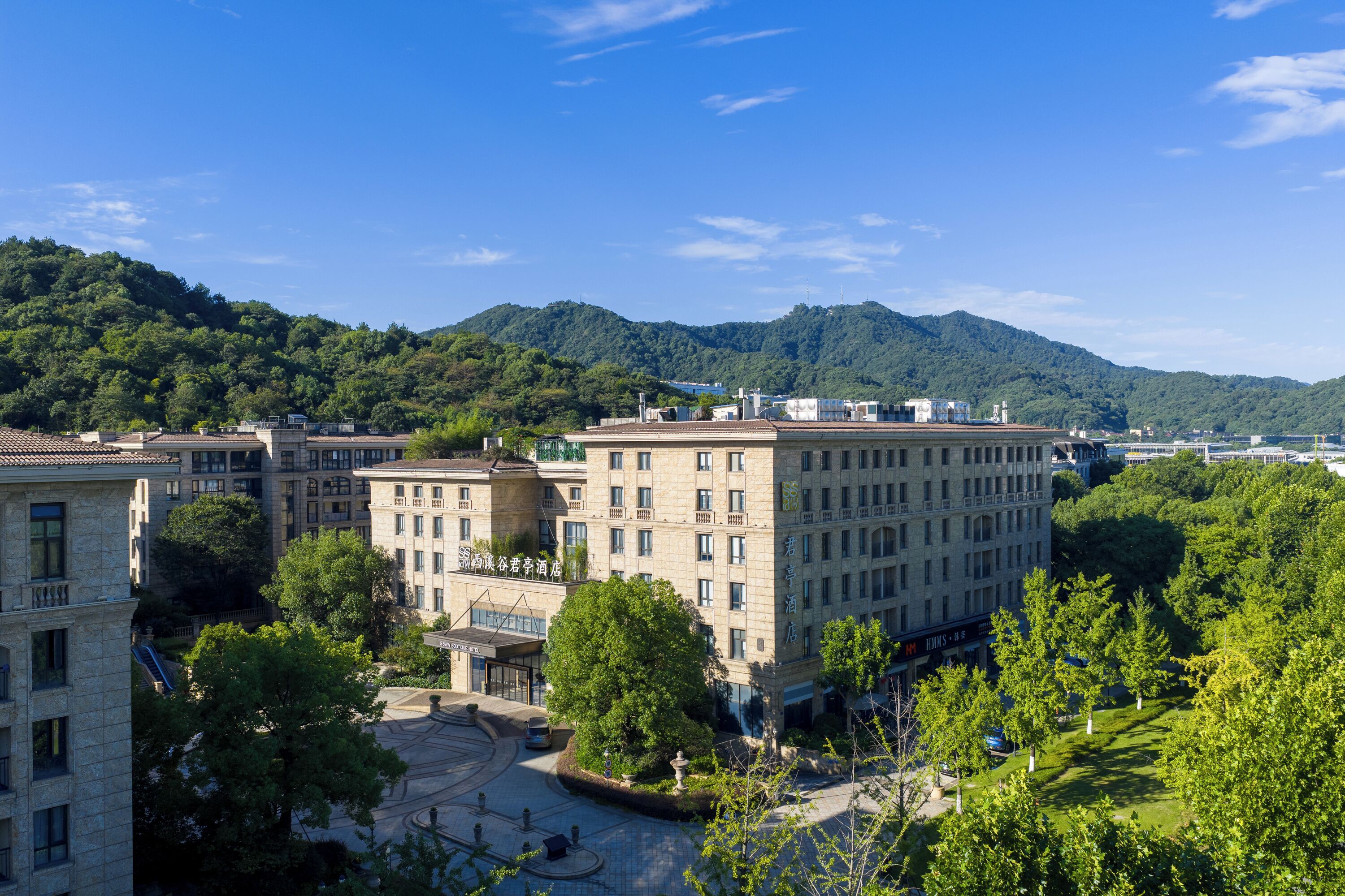A hotel with multiple floors, a courtyard, and a mountainous backdrop.