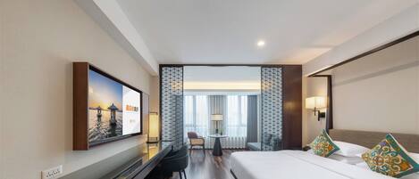 Una habitación de hotel con cama, escritorio, televisor y vistas al exterior.