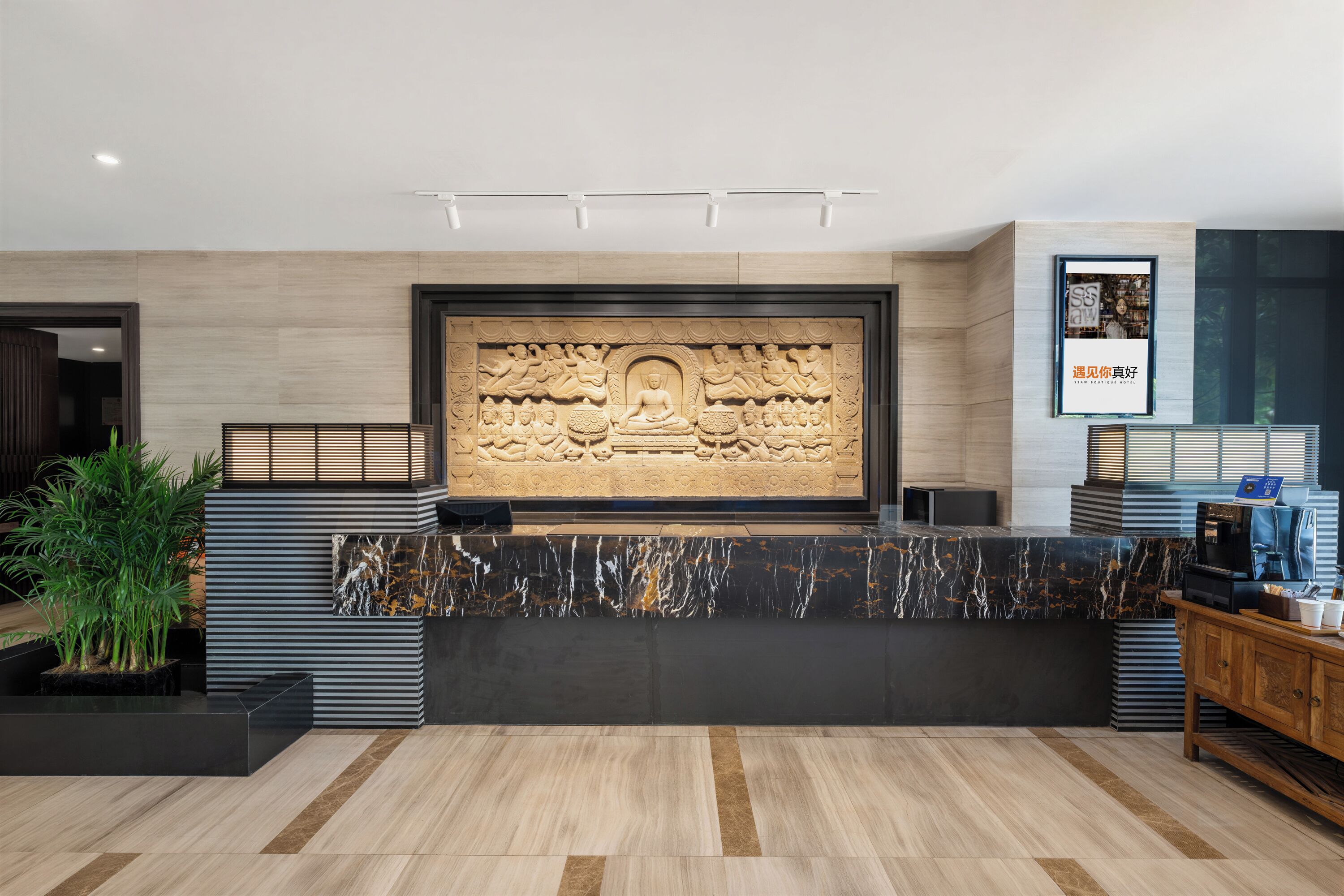 A reception area with a large carved wall, a reception desk, and a framed poster.
