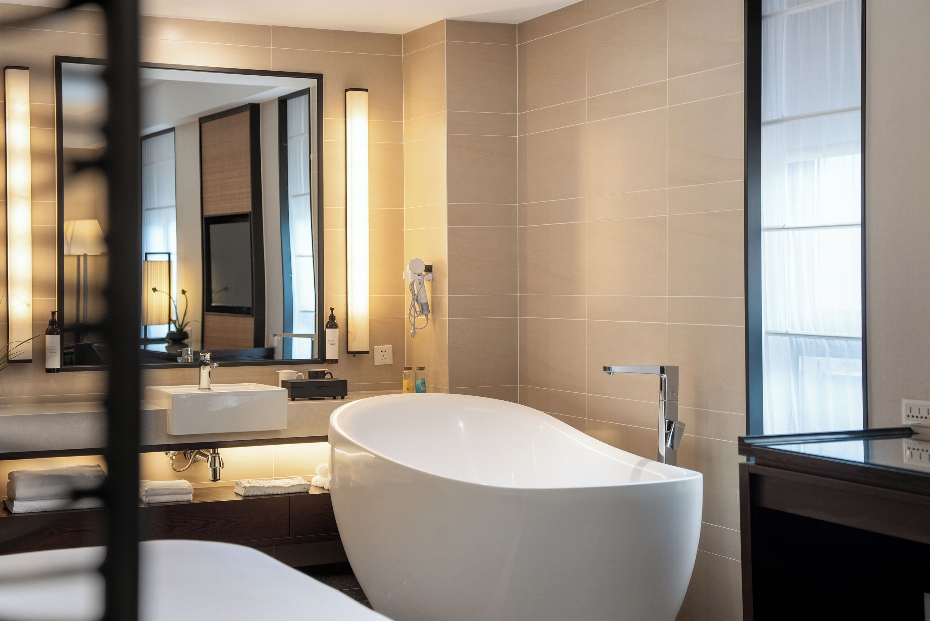 A modern bathroom with a freestanding bathtub, a large mirror, and a vanity with a sink.