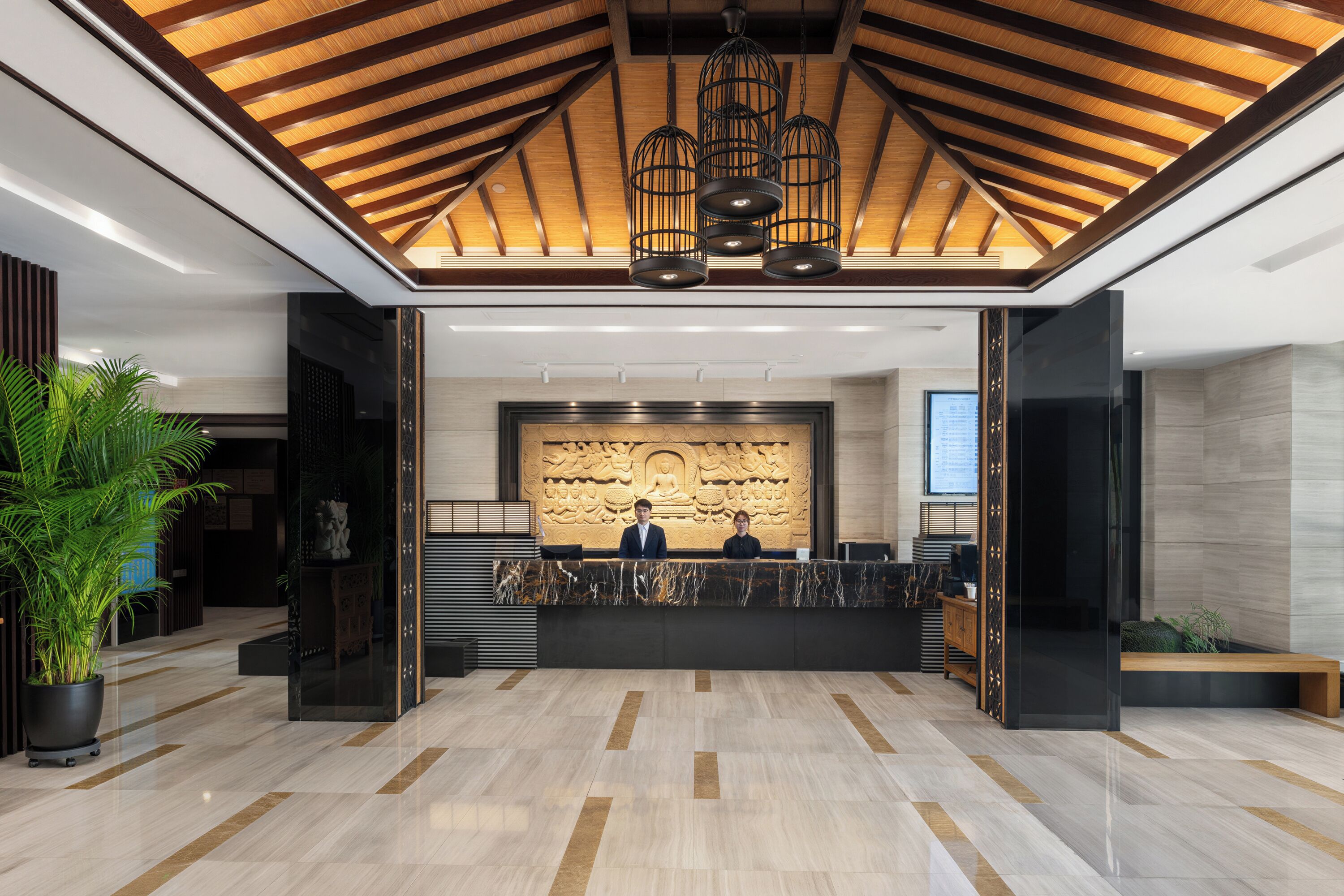 A reception area with a marble floor, a reception desk, and a wall with a relief sculpture.