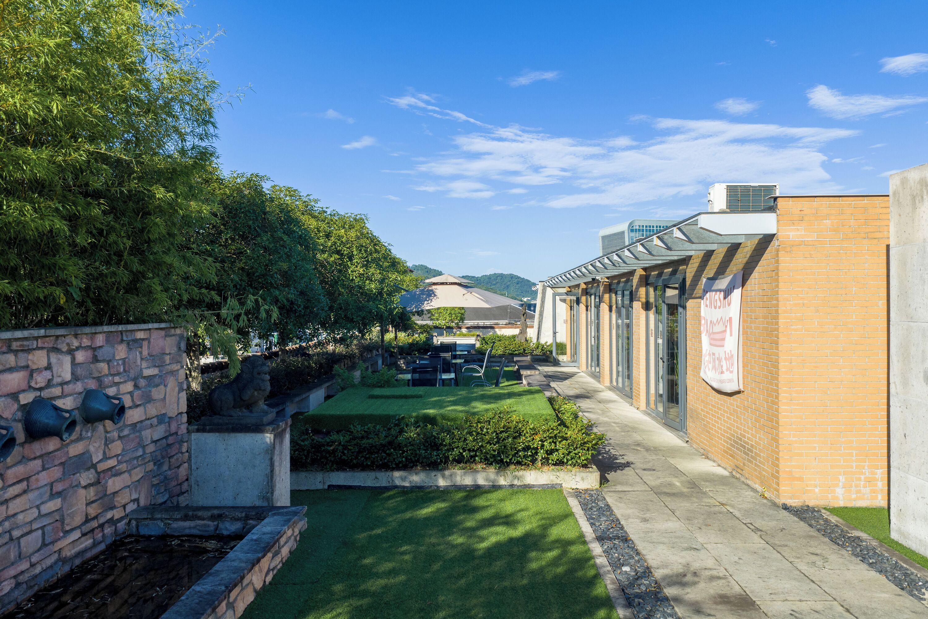 A courtyard with a brick building, a stone wall, and a statue.
