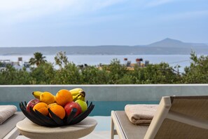 A fruit bowl on a table with a pool and a mountain view in the background. - Bella Casa - Newly Built Designer Villa (Kalyves)