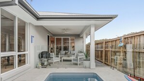 Un patio moderno al aire libre con piscina, zona de estar y valla de madera.