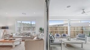 Un salón amplio con un gran ventanal corredera que da a un patio exterior.