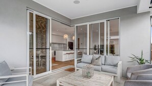 Una sala moderna con sofá, mesa de centro y puertas correderas de vidrio que dan a una cocina.