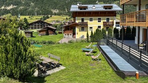 Eine Berglodge mit Balkon, einem Rasen und Blick auf die umliegenden Berge.