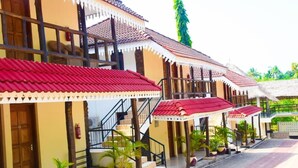 Un edificio con varias estructuras de techo rojo, una escalera y plantas en macetas.