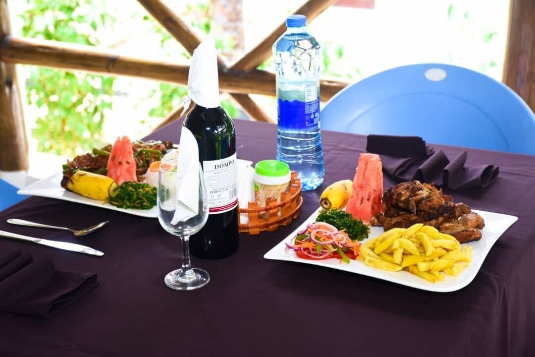 A table set with a variety of dishes, including a banana, salad, and meat, along with a bottle of wine and a water bottle.