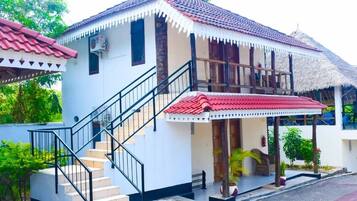 A two-story building with a red-tiled roof, a staircase with black railings, and a covered porch area.