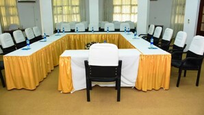 Un salón de conferencias con una larga mesa, varias sillas y botellas de agua.