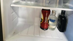 Un refrigerador abierto con copas de vino, una lata de Absolut Vodka y dos botellas.