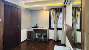 Una cocina compacta con estufa integrada, un lavamanos pequeño y un ventanal con cortinas.