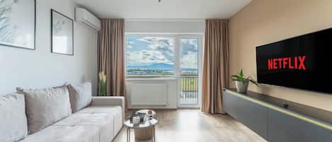 Appartamento Deluxe, vista città | Area soggiorno | TV a schermo piatto 125 cm con canali via cavo, Netflix