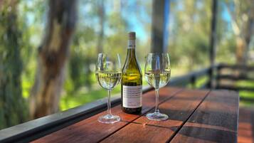 A wooden table with a bottle of white wine and two glasses on it.