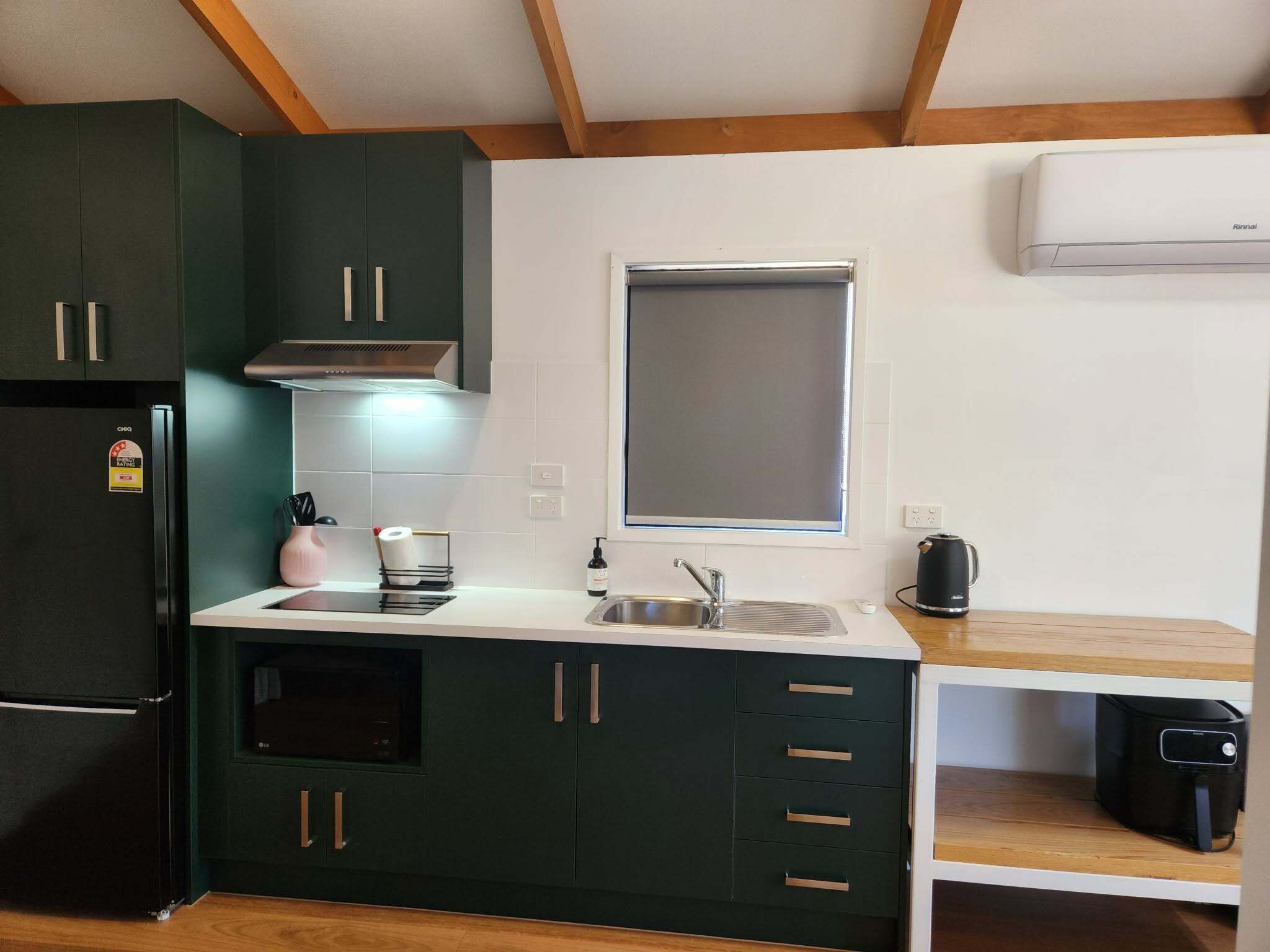 Una cocina compacta con armarios oscuros, un lavamanos de acero inoxidable, una ventana y un horno empotrado.