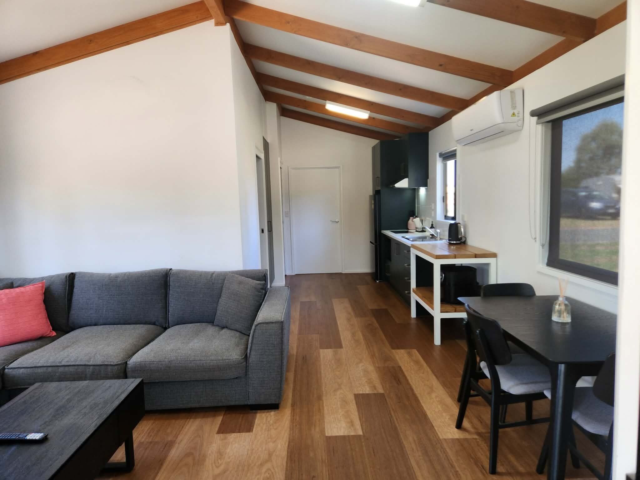 Un espacio habitable compacto con sofá, una mesa de comedor y zona de cocina.