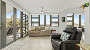 Un salón amplio con un sofá color beige, un sillón de cuero negro y una mesa de comedor.