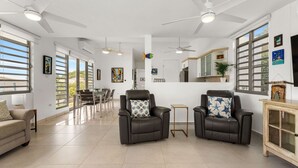 Amplia sala de estar con dos sillones de cuero, un comedor y una cocina.