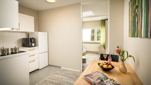 Een moderne keuken met witte kastjes, een koffieapparaat en een eethoek met een tafel gedekt voor twee personen.
