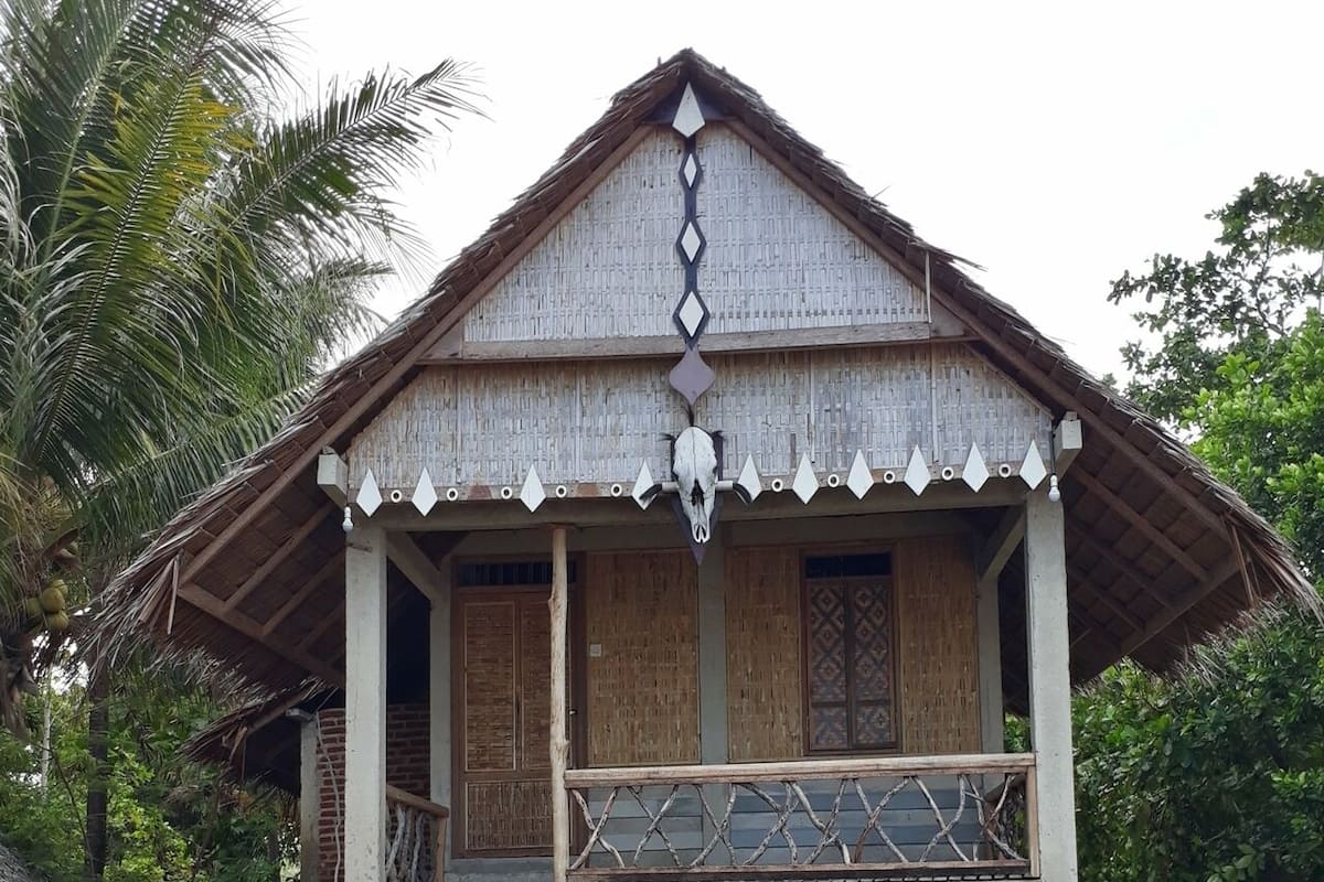 Una casa de dos pisos con un balcón de madera y una escalera que conduce a la entrada.